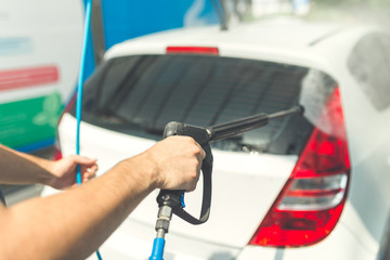 Rear lights and trunk washing with pressurized water in car wash outdoors.