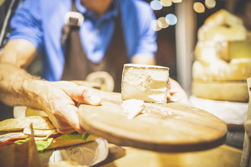 Salesman Holding Cutting Board With Cheese outdoors.
