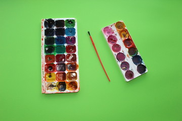paint on a green background. Watercolor and colored objects for school and creativity.