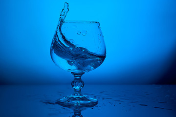 glass of water with splash on the lighting blue background