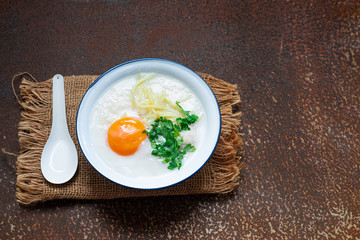 Delicious Rice soup with meat, egg and herbs on rusty metal wall with copy space.,hot food and healthy meal concept