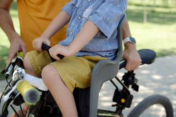 Obraz premium The child sits in a child seat on a bicycle close-up