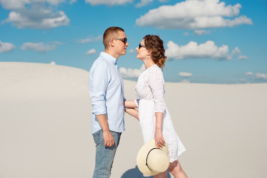 Young couple enjoying the sunset in the dunes. Romantic traveler walks in the desert. Adventure travel lifestyle concept.
