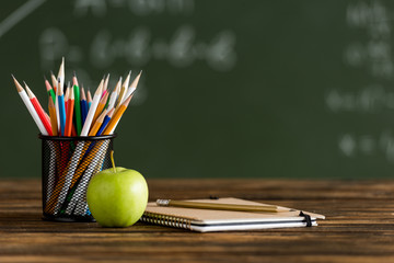 Back to school. Notebook, apple and colored pencil on school table