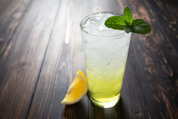 Glasses of lemon soda with ice and fresh mint on wooden table.