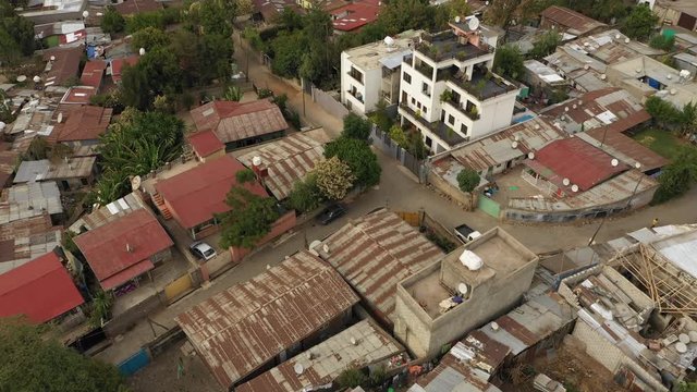 Tilted drone flight over luxurious villa contrasting with surrounding homes with rooftops made of corrugated sheets in residential neighborhood in Addis Ababa, Ethiopia Africa