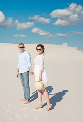 Young couple enjoying the sunset in the dunes. Romantic traveler walks in the desert. Adventure travel lifestyle concept.