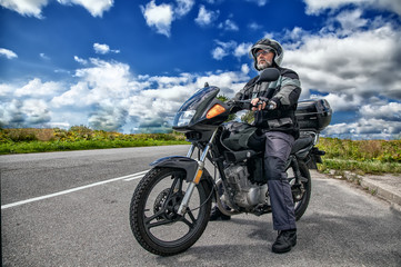 elderly motorcyclist sitting on his motorcycle on the open road