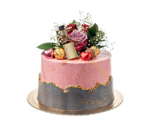 Conceptual birthday cake with flowers and a bottle of whiskey. On a white background.