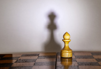 chess pawn with the shadow of a queen