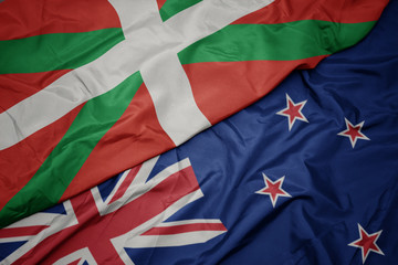 waving colorful flag of new zealand and national flag of basque country.
