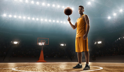 Professional basketball player in sports uniform on basketball court with a ball
