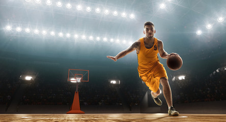 Professional basketball player dribbling. Floodlit sports arena