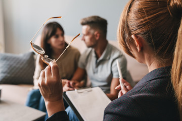 Photo of thinking caucasian couple having conversation with psychologist on therapy session in room