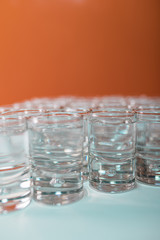 Vertical image of tasty tequila served in shots on a white table and an orange background