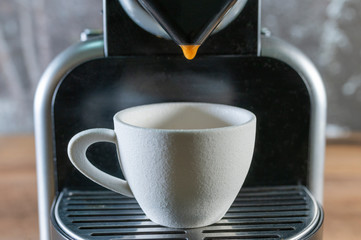 Detail of a coffee machine pouring coffee into a white cup