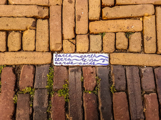 Royal Delft blue brick with Earth written on it in 3 different languages in the pavement