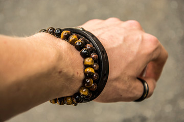 Beaded bracelets and leather bracelet on a wrist with a tungsten ring on the thumb