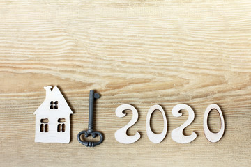 home with number 2020 and key on wooden table, top view. round date to start a comfortable life