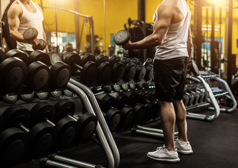 Closeup of young fitness trainer with dumbbells