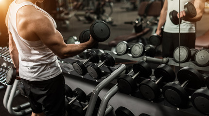 Closeup of young fitness trainer with dumbbells