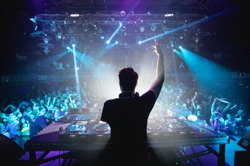 Poster Silhouette of DJ in nightclub with hands up, shot from behind © amacrobert