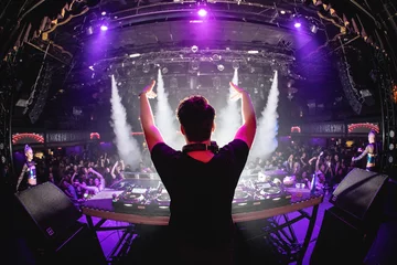 Foto op Plexiglas DJ in nightclub with hands up and cryo canons, shot from behind © amacrobert