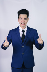 Portrait handsome young asian .businessman wearing a blue suit showing thumbs up sign isolated on grey background in studio. Asian man people. business success concept.