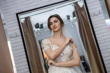 Fototapeta premium Beautiful bride in salon posing in wedding dress