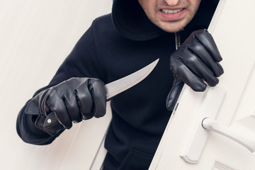 Angry thief with knife, breaking and entering into a victim's home, cropped image, close up