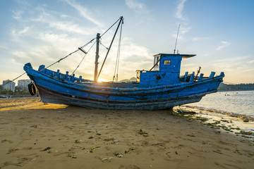 Naklejka na ściany i meble Beautiful sunrise on an old wooden fishing boat on the beach
