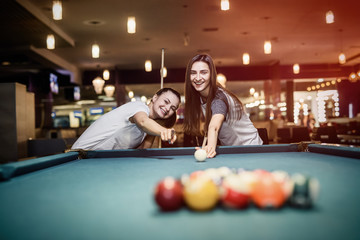 Friends playing billiard aiming on ball in pub