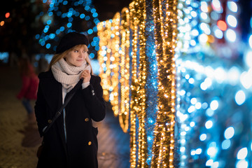 Young woman walking along illuminated alley during Christmas