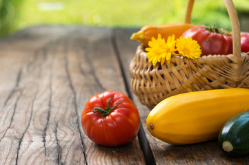 Fresh tomatoes and zucchinis on rustic wooden background. Copy space.