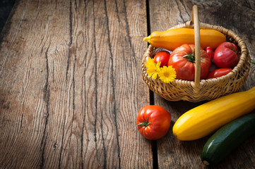 Freshly harvested tomatoes and zucchinis on rustic wooden background. Autumn harvest. Copy space
