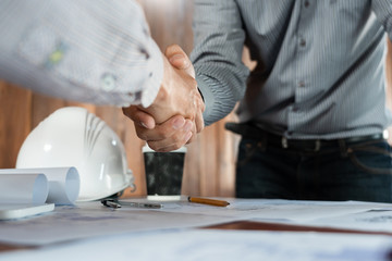 Architect and engineer construction workers shaking hands while working for teamwork and cooperation concept after finish an agreement in the office construction site, success collaboration concept.