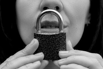 Conceptual portrait of a woman keeping silence with lock over her mouth. caucasian woman keep mouth...