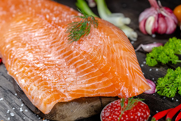 a large piece of red fish fillet with vegetables and spices and fresh herbs, stand and lie, from...