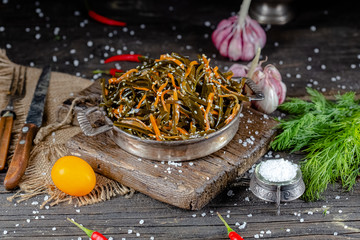 seaweed and carrot salad, mayonnaise sauce, in a rustic rustic bowl bowl, fork knife spoon, spices,...