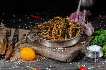 seaweed and carrot salad, mayonnaise sauce, in a rustic rustic bowl bowl, fork knife spoon, spices,...