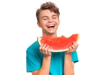 Portrait of teen boy eating ripe juicy watermelon and smiling. Cute caucasian young teenager with slice healthy watermelon. Funny happy child wearing blue t-shirt, isolated on white background.