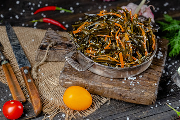 seaweed and carrot salad, mayonnaise sauce, in a rustic rustic bowl bowl, fork knife spoon, spices,...