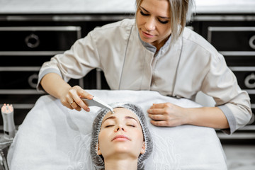 Female cosmetologist making vacuum hydro peeling to a woman at the luxury beauty salon. Concept of a professional facial treatment