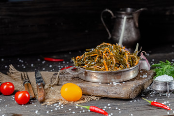 seaweed and carrot salad, mayonnaise sauce, in a rustic rustic bowl bowl, fork knife spoon, spices,...