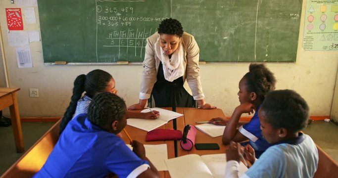 Female teacher and young pupils working in class 4k