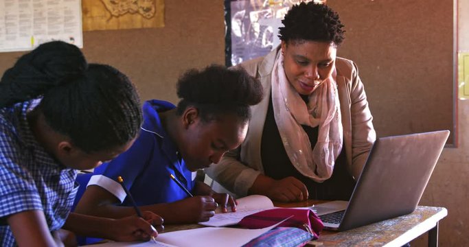 African woman teacher helping schoolchildren in a lesson at a township school 4k