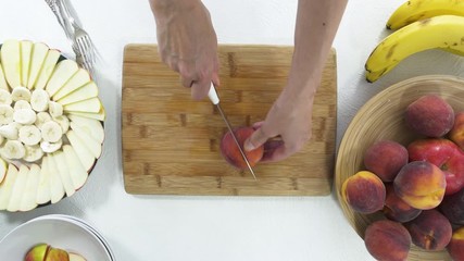 Peaches on a Wooden Cutting Board. Woman Slicing Fresh Ripe Organic Peaches. Close Up, View from Above, on White Background. Fruit Salad Preparation, Fruit Platter, Dessert