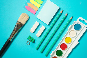 Back to school mock up. Flat lay composition with a brush, watercolor, pencil, sticker, eraser. Isometric concept on blue background. Pop art. School supplies. overhead. Branding mock up stationery
