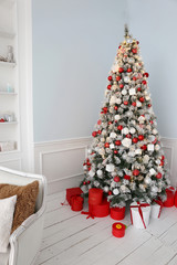 Elegant Christmas tree with white and pink toys and gift boxes in the bedroom of luxury apartments