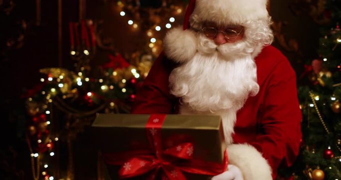 Santa Claus takes toys out of the gift box and hangs them on the Christmas tree. Christmas and New Year time.